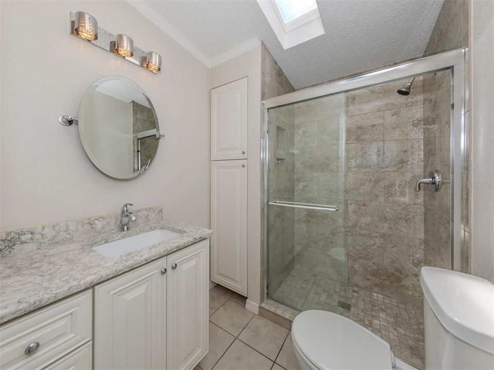 Guest bath with custom vanity, quartz counter, custom linen closet with pull outs and porcelain tile shower.