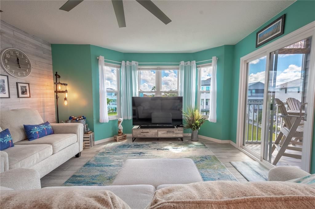 The living room features a neutral tone, wood plank tile floor.