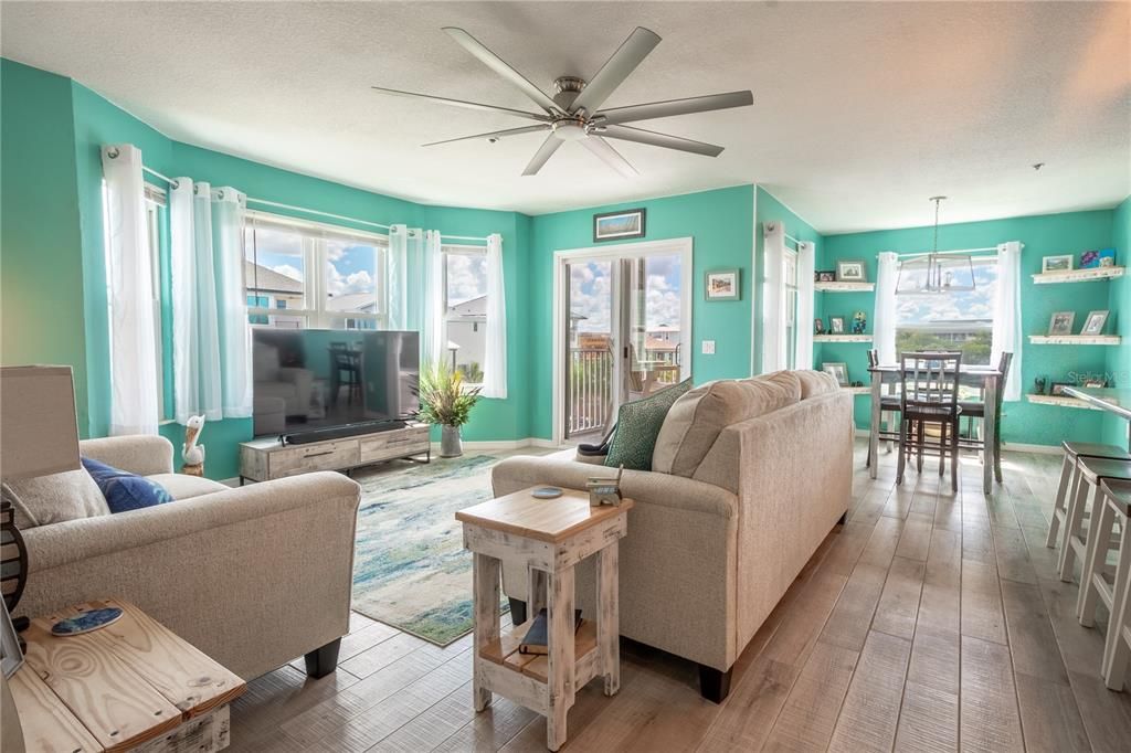 The living room has a bay window and sliding glass doors that provide abundant natural light. Keeping it "cool" is a modern 8-blade ceiling fan.