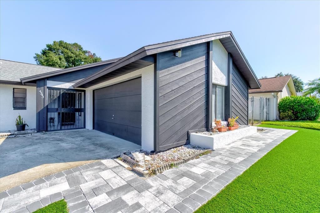 View of 2 car garage and newly added pavers and artifical turf.