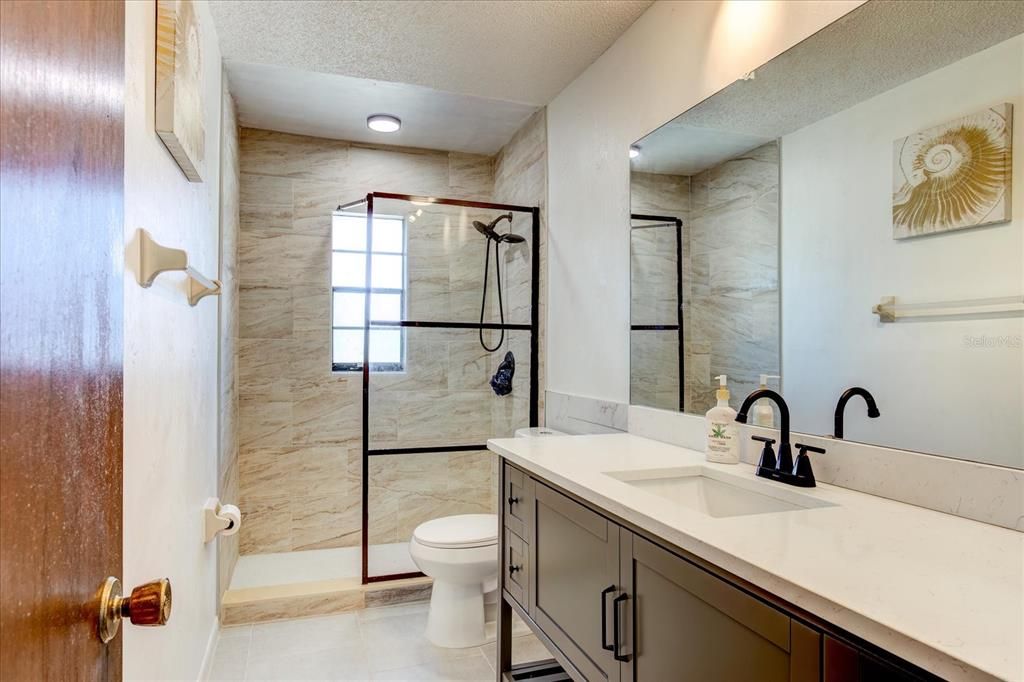 Fully renovated guest bathroom with newly created shower, new tile and classic fixtures and lighting.