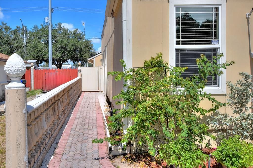 A brick paver walkway leads to the vinyl fenct gate to backyard oasis