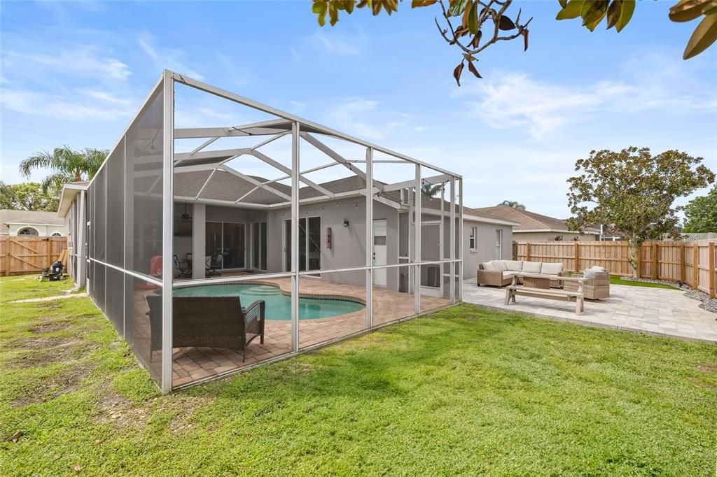 View of enclosed pool and paved backyard