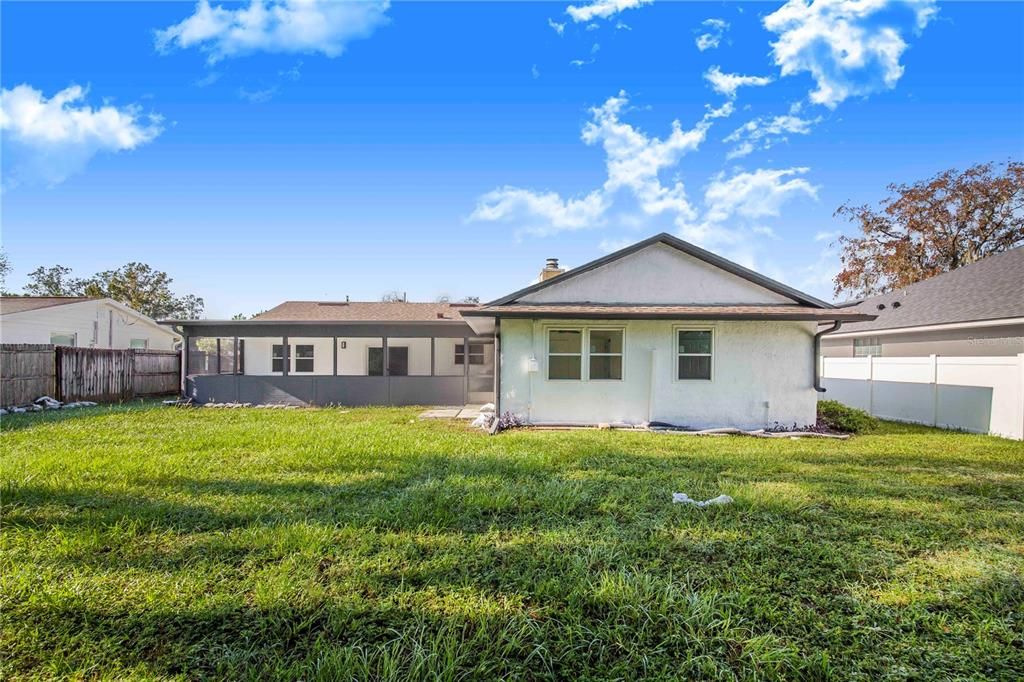 Rear of the home features a large back yard with fenced sides and mature vegetation line the rear lot line