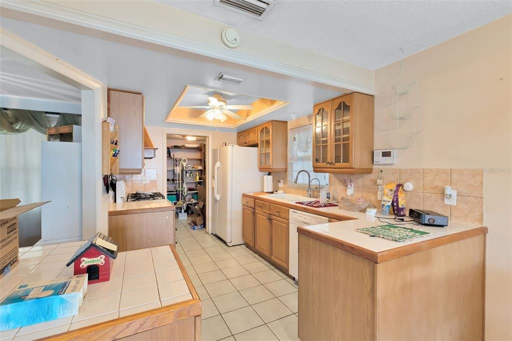 The kitchen boasts tile countertops, a tile backsplash, and a stylish tray ceiling.