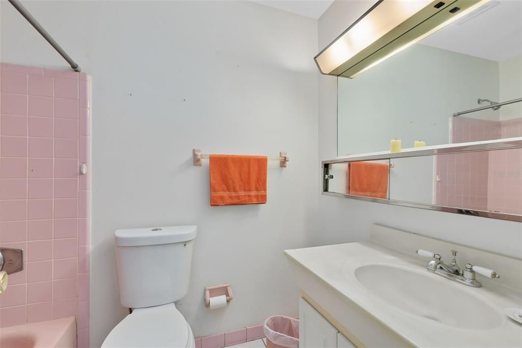 The secondary bath has a tub/shower combo adorned in beautiful pink retro tile.