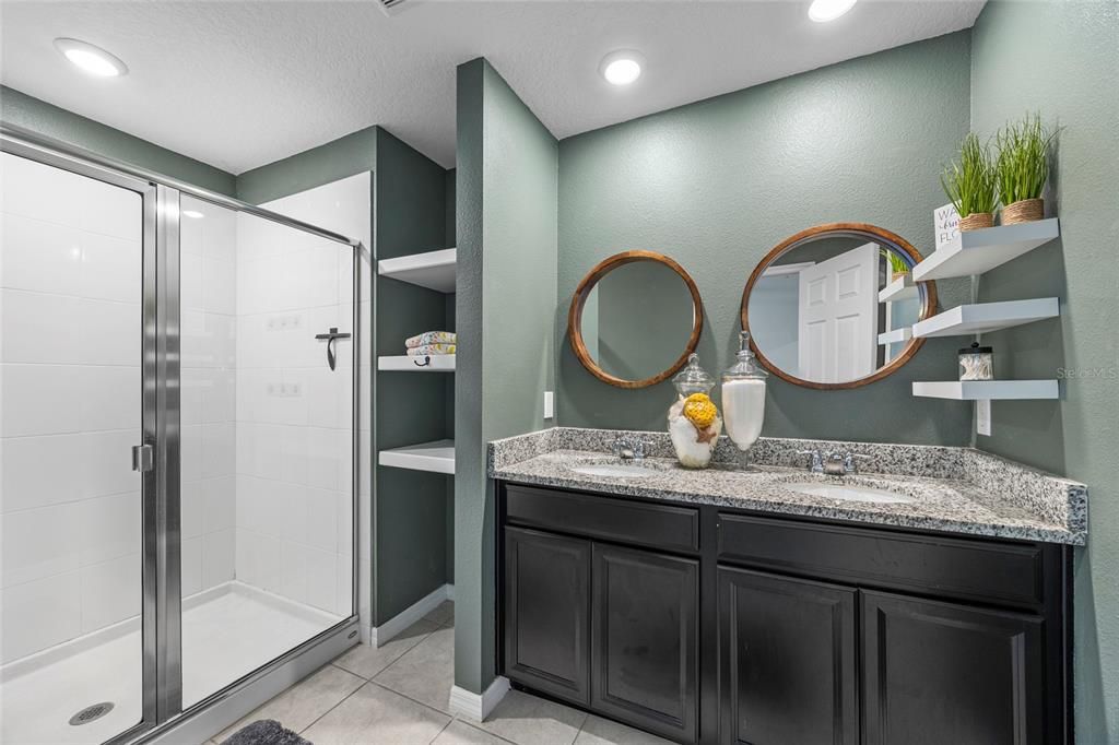 Double sinks in owners suite with walk-in shower and toilet closet