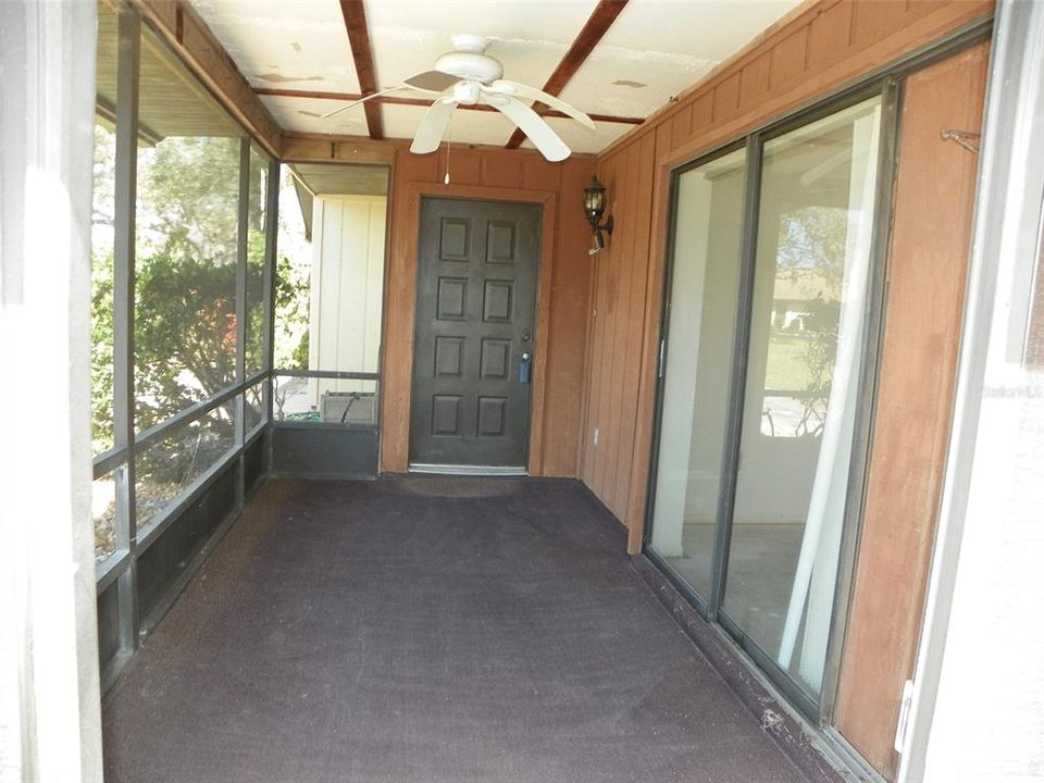 Covered/Screened lanai area leading to front door. Guest bedroom on right.