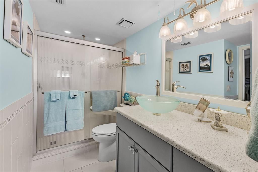 Guest bath featuring tile walls, vanity, walk in shower, tile flooring