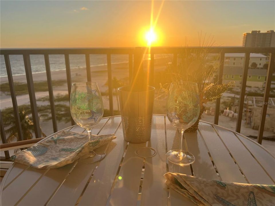 Balcony at dusk featuring a view of the beach and a water view