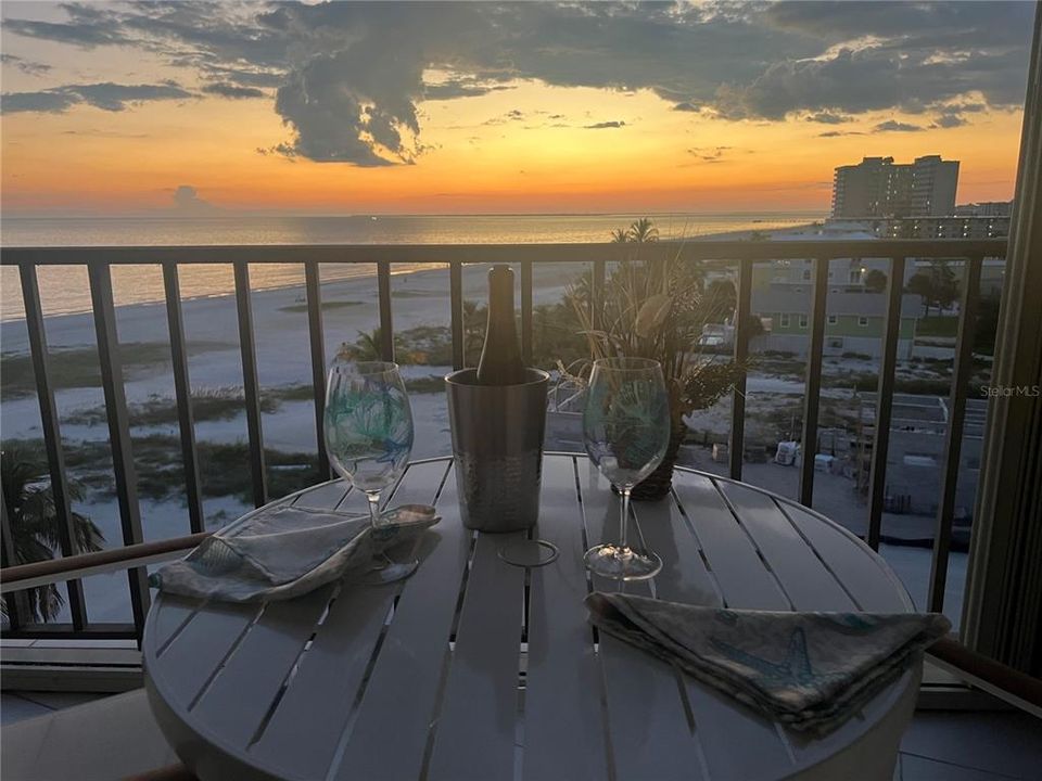 Balcony at dusk featuring a view of the beach and a water view