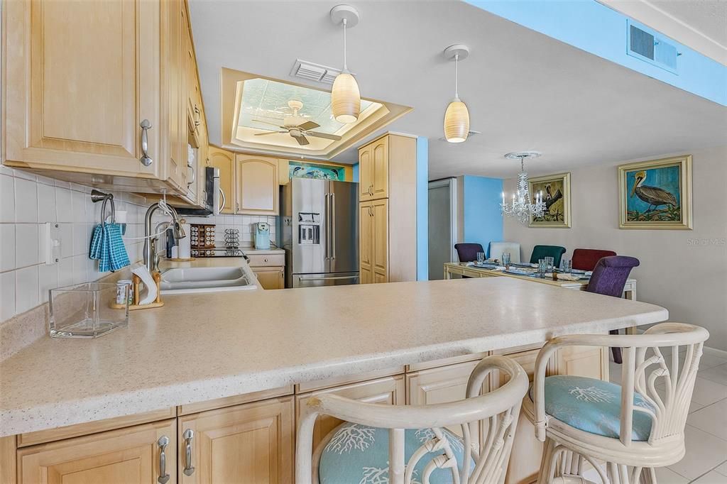 Kitchen featuring light brown cabinets, tasteful backsplash, decorative light fixtures