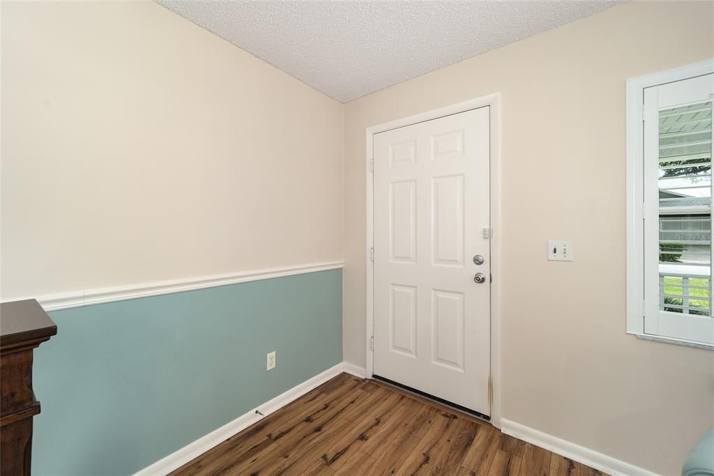 Looking back to the front door.  Their are chair railings in the living area and wooden shutters on the windows.