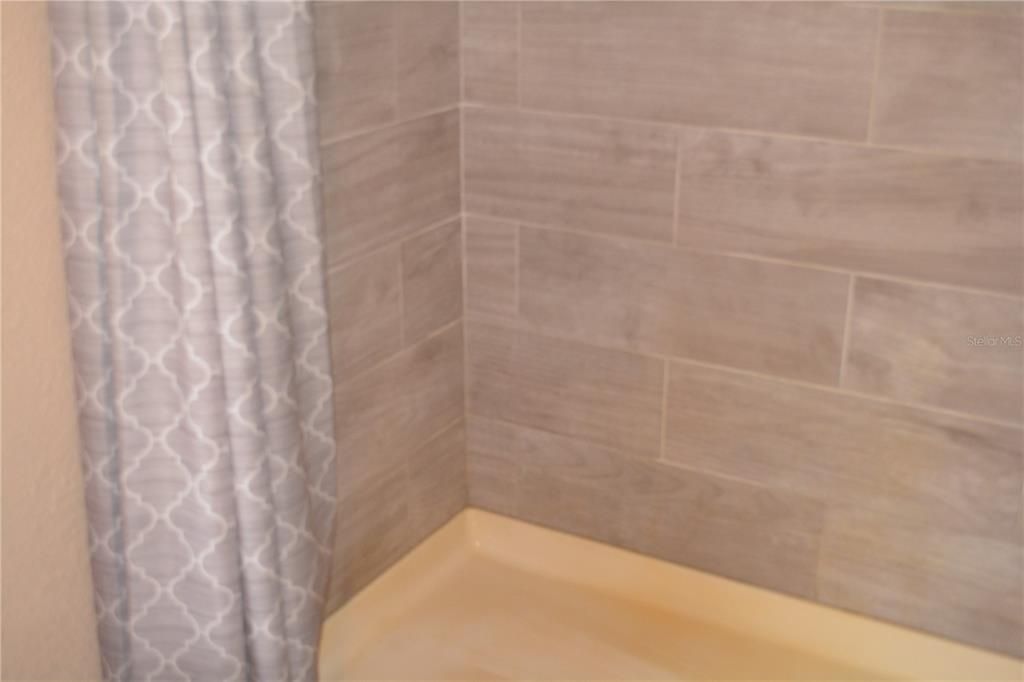 Shower with tiled walls in the primary bedroom