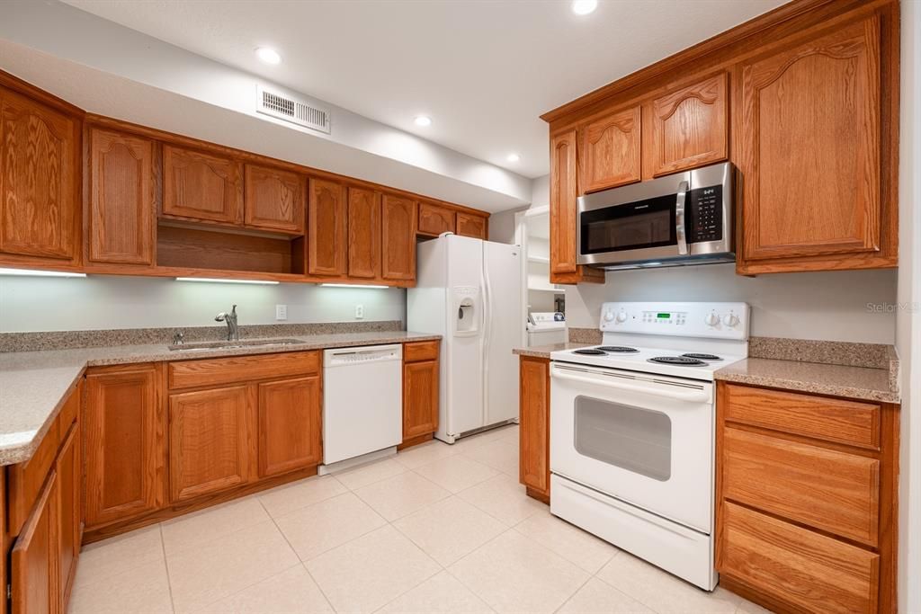 The comfortable kitchen surrounds the home chef with solid wood cabinetry, quality appliances (that include a new microwave in 2024!) and granite counters.