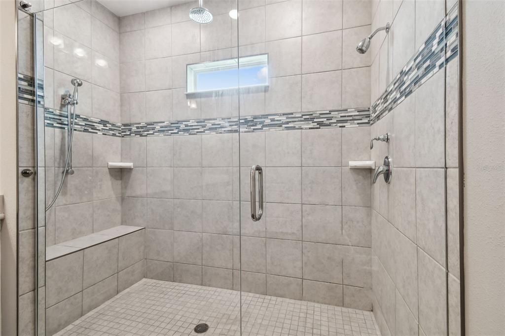 Primary bath. Double shower. Decorator tile. Three shower heads. Built-in bench.