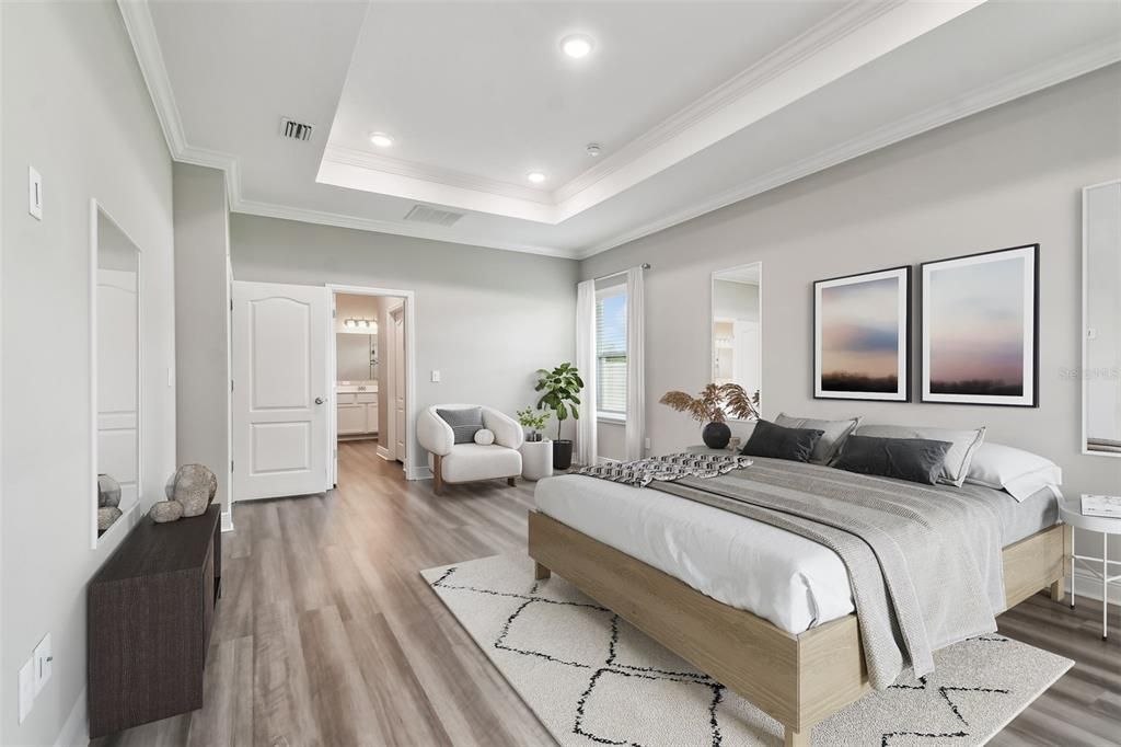 Spacious primary bedroom with tray ceiling, recessed lighting and crown molding. Luxurious en-suite bath.