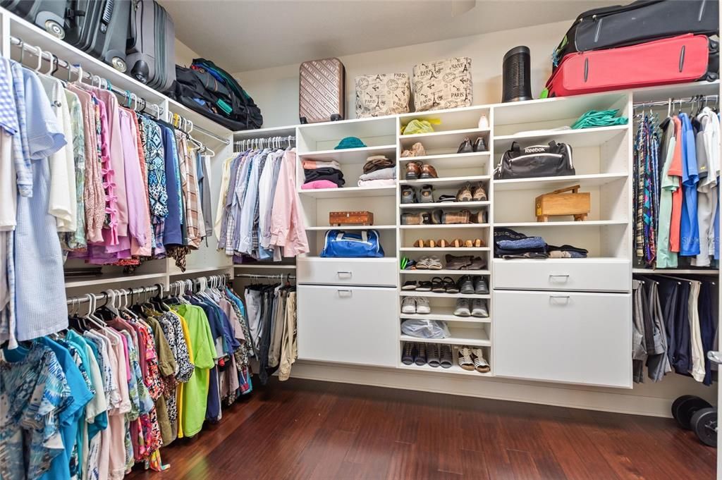 Primary bedroom walk-in closet has custom built-ins and ceiling fan