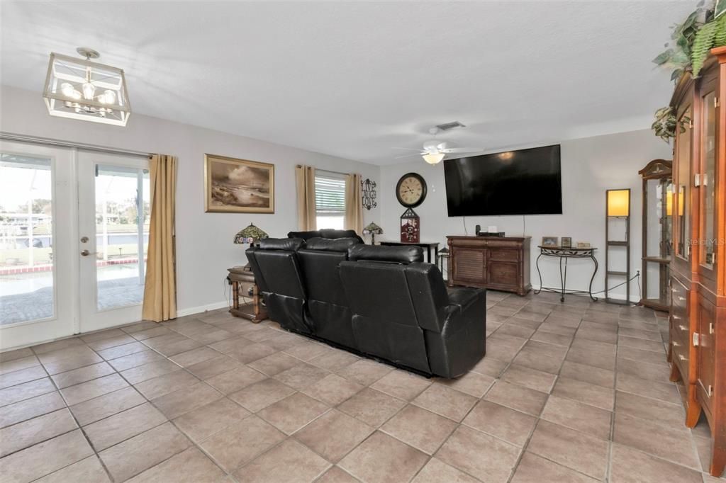 Living room with tile flooring and French doors to lanai and pool.