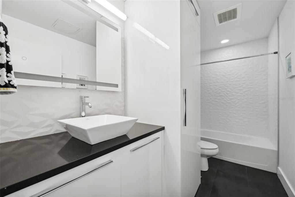 Guest bath has been completely updated including a vessel sink, frameless mirror, and Porcelanosa 3D wall tiles imported from Spain.