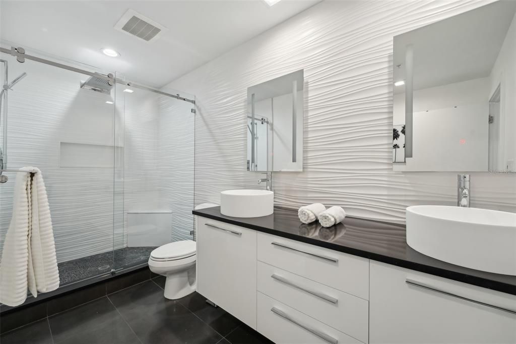 Luxury awaits in the extra large bathroom which features glass shower, frameless mirrors, dual sinks and Porcelanosa 3D wall tiles imported from Spain.