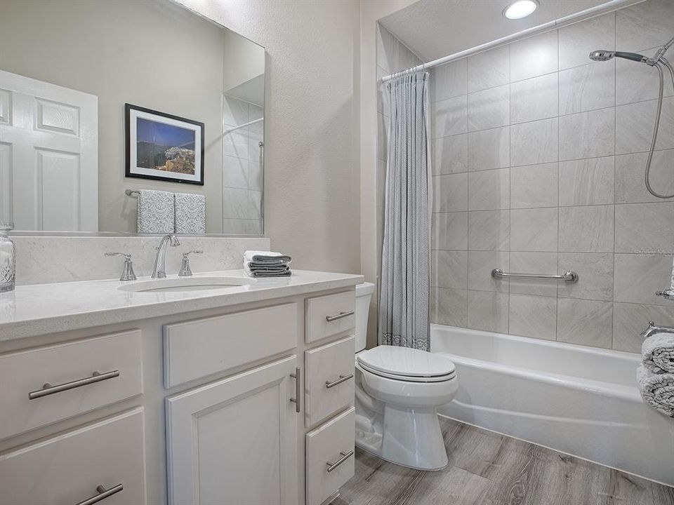 THE GUEST BATH OFFERS THE SAME LOVELY QUARTZ AND A TILED SHOWER/TUB.