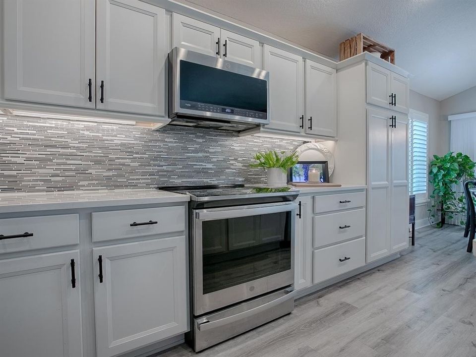 WHITE CABINETRY WITH TIMELESS MATTE BLACK HARDWARE, QUARTZ COUNTERTOPS, AND GLASS TILE BACKSPLASH.