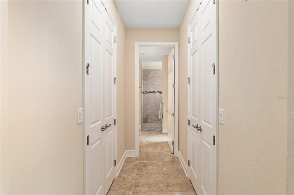 Hallway with a his and hers closet leading to the spacious primary bathroom