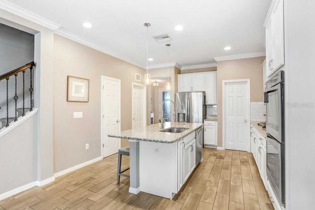 Kitchen with 42 inch cabinets, built on over, gas cooktop, granite countertops, island with sitting area, stainless appliances, with gorgeous wood plank porcelain tile