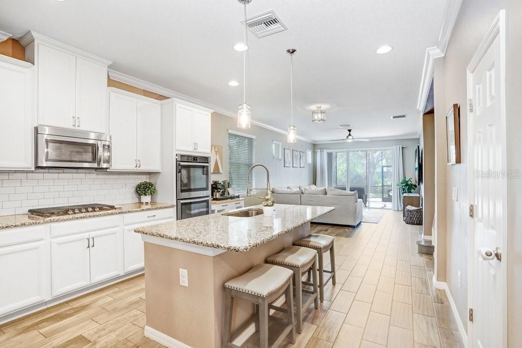 Kitchen with 42 inch cabinets, built on over, gas cooktop, granite countertops, island with sitting area, stainless appliances, with gorgeous wood plank porcelain tile