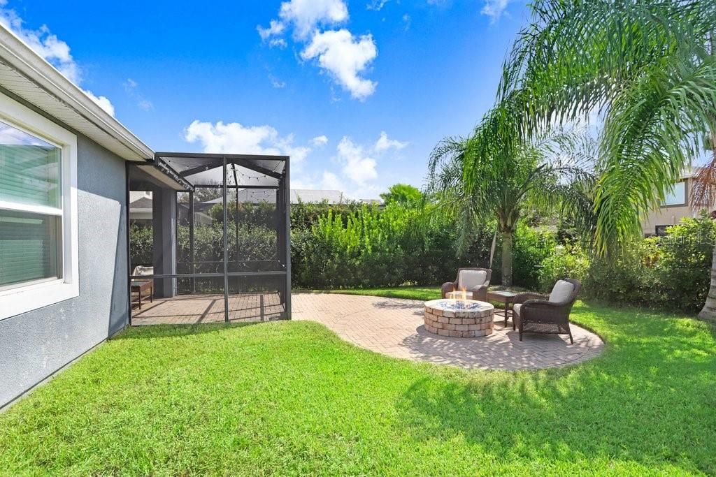 Back yard with screened lanai with beautiful pavers that lead to a sitting area with fireplace