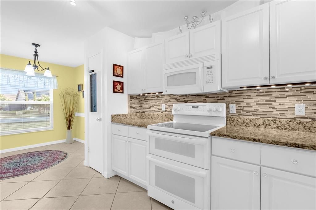 Spacious kitchen- White solid wood cabinets, White Appliances, Granite Counters, Glass Backsplash, LED lighting with breakfast nook