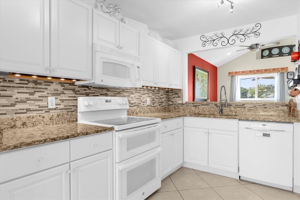 Spacious kitchen- White solid wood cabinets, White Appliances, Granite Counters, Glass Backsplash, LED lighting with breakfast nook