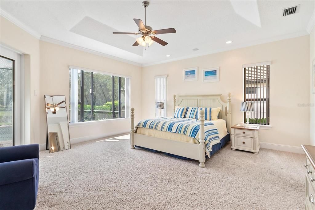 Primary Bedroom with Tray Ceilings and French Doors that lead to the Lanai and Pool Area