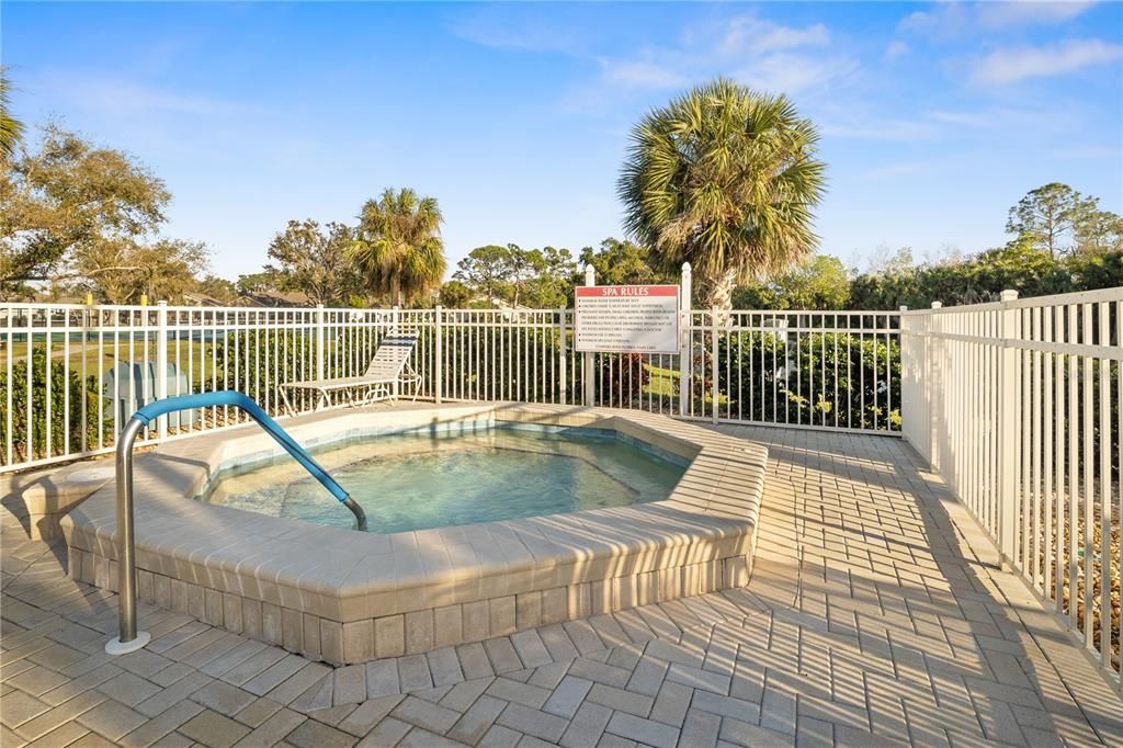 RELAXING HOT TUB OVERLOOKS A LAKE WITH A FOUNTAIN.