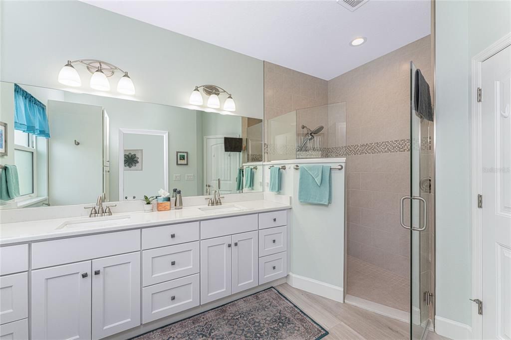 Primary bathroom has a step-in shower and double vanity with Quartz countertop