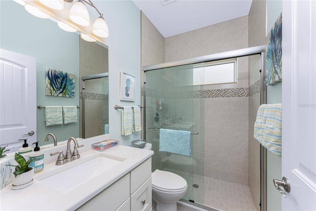 Guest bathroom also has an all-tile step-in shower with sliding-door glass enclosure