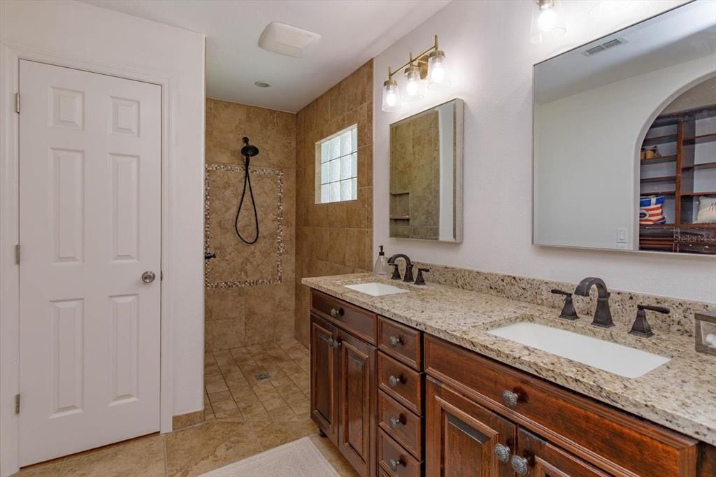 Primary Bathroom with dual sink granite counter vanity and walk in shower