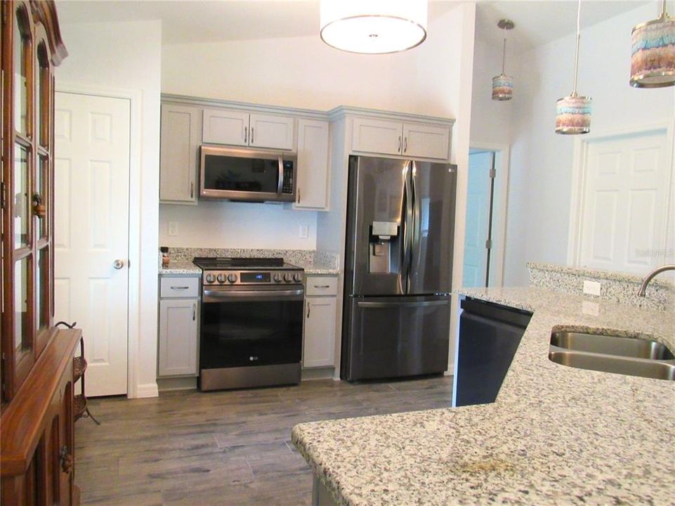 A Chef's Delight Culinary Kitchen w/ Cathedral Ceiling, Porcelain Floor, Custom Display Shelves & Stainless Steel Appliances.