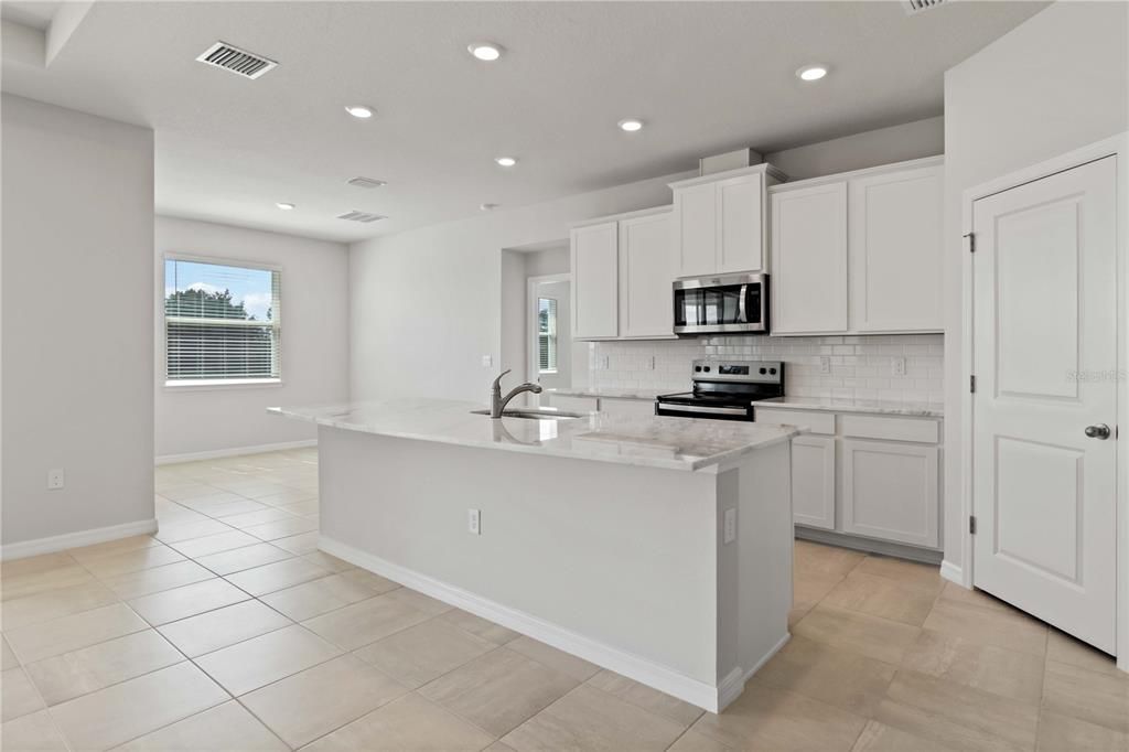 Bright White Kitchen with Stainless Steel Appliances, a huge island and Breakfast Nook.