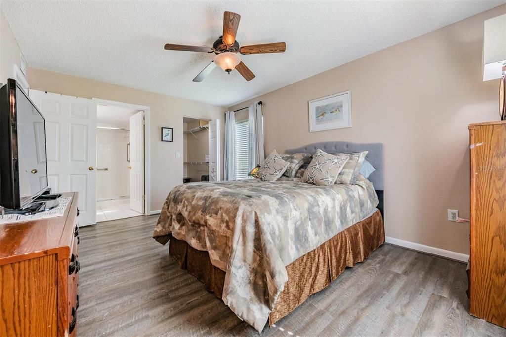 The spacious primary bedroom offers serene pond views, stylish laminate floors, a large walk-in closet, and a light-filled ensuite bath with a stand-up shower.