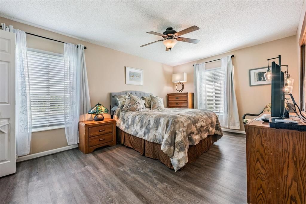 The spacious primary bedroom offers serene pond views, stylish laminate floors, a large walk-in closet, and a light-filled ensuite bath with a stand-up shower.