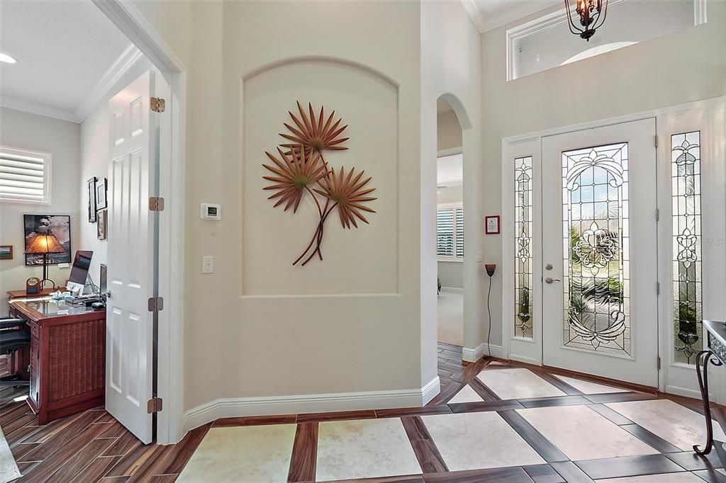 The foyer offers a very ineresting design with custom installed  wood look tile with travertine tile inlay. Architectural details such as niches for displaying artwork and curved details.