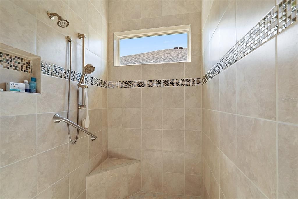 Primary bathroom shower with custom tile accents and grab bar