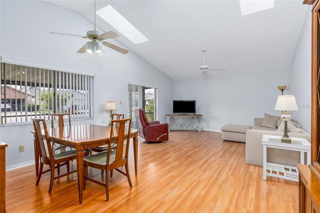 This dining room and living room combo has 2 skylights and a high ceiling.