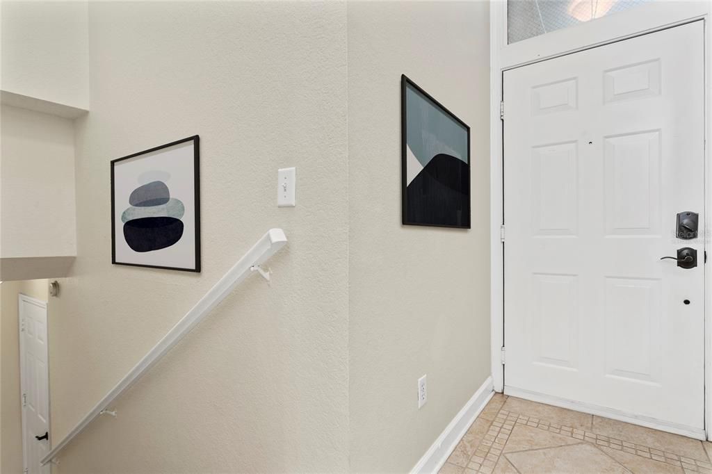 Virtually staged image of accessories in the front entry way, down the stairs leads to your two car garage