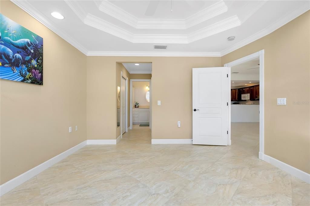 Bedroom with a tray ceiling, ceiling fan, and crown molding