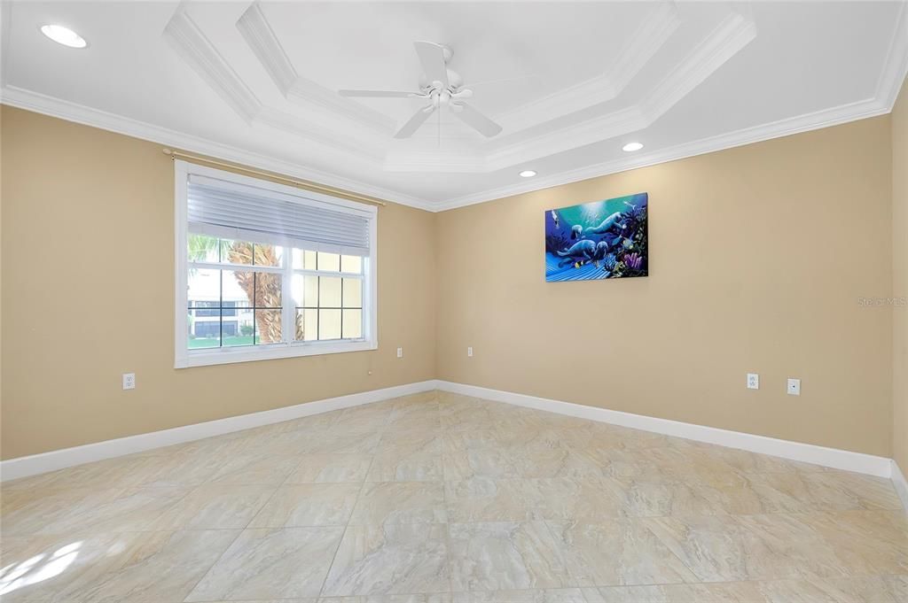 Bedroom with a tray ceiling, ceiling fan, and crown molding