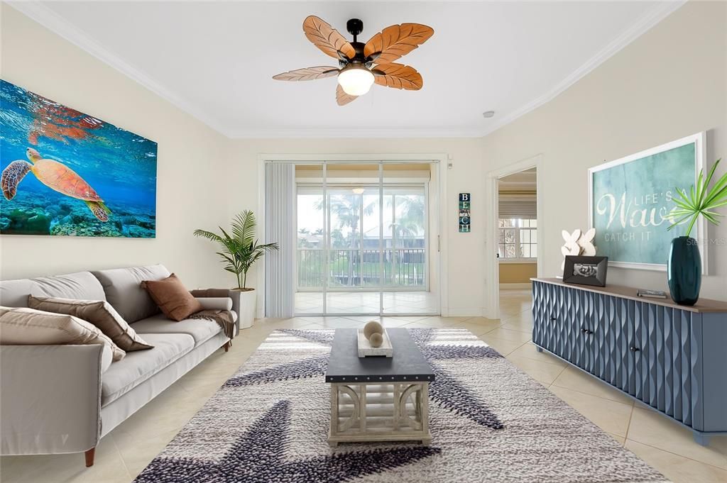 Living room with ceiling fan, light tile patterned flooring, and ornamental molding