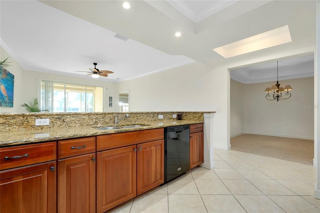 Kitchen featuring light stone countertops, ornamental molding, white appliances, and a tray ceiling